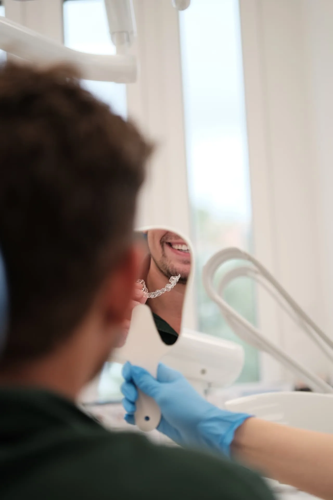 Átlátszó fogszabályozó sín ellenőrzése tükörben az Orim Dental rendelőjében